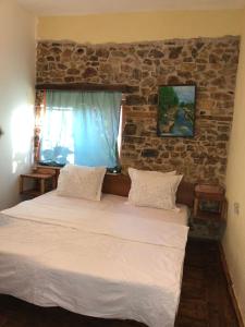 1 dormitorio con 1 cama grande y pared de ladrillo en Rosas Home en Pogradec