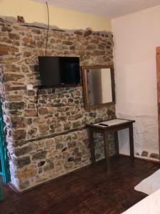a tv on a stone wall with a table and a mirror at Rosas Home in Pogradec