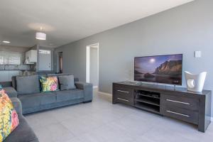 a living room with a couch and a flat screen tv at Cap du Mont in Bloubergstrand