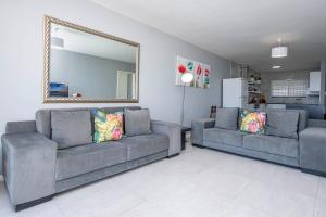 a living room with two couches and a mirror at Cap du Mont in Bloubergstrand +15 photos