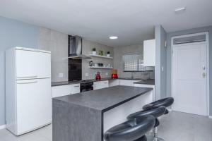 una cocina con electrodomésticos blancos y taburetes negros en Cap du Mont en Bloubergstrand