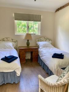 a bedroom with two beds and a table and a window at *New* Hartest Vineyard 2 bed cottage with parking in Hartest