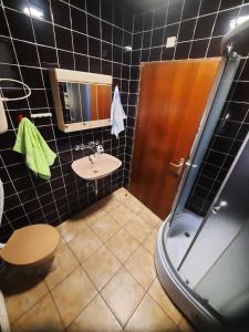 a black tiled bathroom with a sink and a shower at Royal Rose smeštaj in Bela Crkva