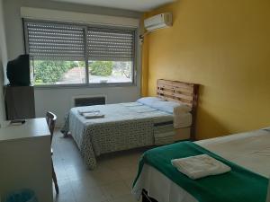 1 dormitorio con 2 camas y ventana en Pousada Terra Sul, en Porto Alegre