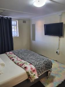 Schlafzimmer mit einem Bett und einem Flachbild-TV in der Unterkunft MJ ACCOMODATION in Kapstadt