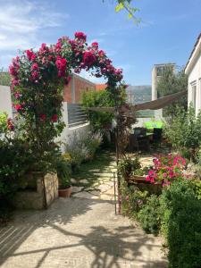 einen Garten mit rosa Blumen und einer Pergola in der Unterkunft Quite beautiful apartment in the Split Neda with 4bedrooms in Solin