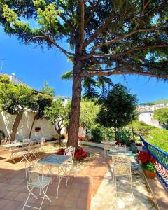 a group of chairs and tables under a tree at Residence Villa Giordano in Vietri sul Mare