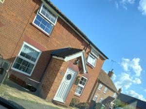 a brick building with a white door on it at 1 ivy cottages the street norton subcourse NR146RS in Norwich