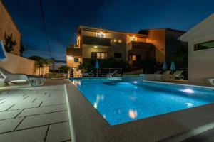 a swimming pool in front of a house at night at Apartments Villa Magdalena in Trogir
