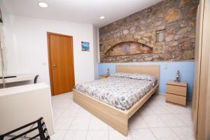 a bedroom with a bed and a stone wall at Hotel Arenauta in Gaeta