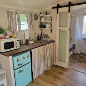 uma cozinha com um micro-ondas e um frigorífico azul em Peaceful Tucson Tiny House Getaway with Backyard em Tucson