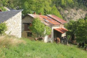 una vieja casa de piedra con dos vacas a su lado en Terre Rouge en Boulc
