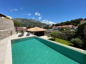 a swimming pool in front of a house at Apartments Kralj Ana in Cavtat