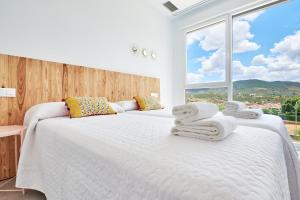 two beds in a bedroom with a large window at 9 NIDOS Céntrica Suites - Nuevo in Plasencia