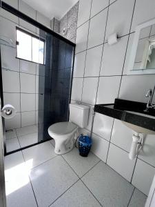 a white bathroom with a toilet and a sink at Pinheiro Flat Hotel in Ibiapina