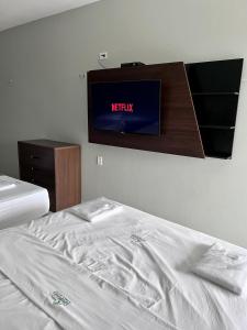 a bed in a room with a television on the wall at Pinheiro Flat Hotel in Ibiapina