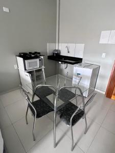 une table en verre et deux chaises dans la cuisine dans l'établissement Pinheiro Flat Hotel, à Ibiapina
