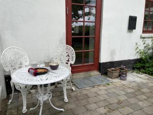 a white table and chairs in front of a door at Vita og Pouls Gård - Guesthouse in Viby