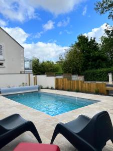 a swimming pool in a backyard with two black chairs at Lamarck Guest in Bourges