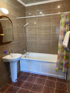 ein Badezimmer mit einem Waschbecken, einer Badewanne und einem Waschbecken in der Unterkunft Victoria Hotel in Aqtau