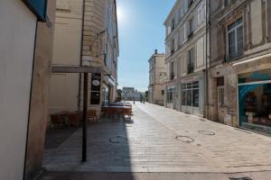 une rue vide avec des tables, des chaises et des bâtiments dans l'établissement Cosy Apparts Saintes, à Saintes