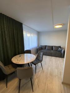 ein Wohnzimmer mit einem Tisch und einem Sofa in der Unterkunft ADI Apartamentai in Panevėžys