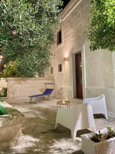un patio con sillas blancas y un banco azul en Villa Ricciardi-Suite familiare 2-zona Ostuni, en Montalbano