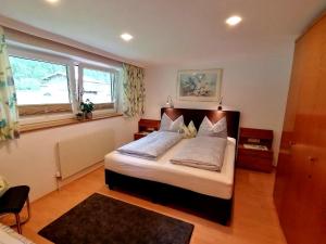 ein Schlafzimmer mit einem Bett mit weißen Kissen und einem Fenster in der Unterkunft Glockenstuhl, Haus in Tux