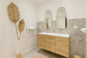 La salle de bains est pourvue d'un lavabo et de deux miroirs. dans l'établissement La Villa l'Escale, somptueuse maison contemporaine, à Angoulême