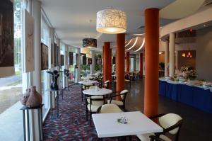 a restaurant with white tables and chairs and orange pillars at Rehabilitation Centre & SPA Draugystės sanatorija in Druskininkai