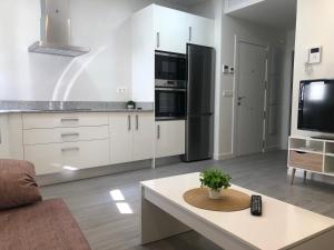 eine Küche mit weißen Schränken und einem schwarzen Kühlschrank in der Unterkunft Apartamento Air Blanc Maracena Centro in Maracena