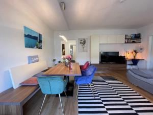 a living room with a wooden table and blue chairs at Seewohnung Lucia - mit Seezugang in Annenheim