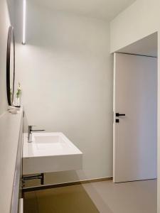 a white bathroom with a sink and a door at Villa Verlengia in Montesilvano