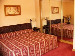 a hotel room with two beds and a mirror at Hotel Don Luis in Madrid