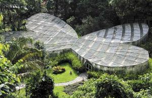 una grande casa di vetro in un giardino di Cabaña los Naranjos con parqueo a Calarcá