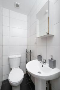 a white bathroom with a toilet and a sink at Flat in London in London