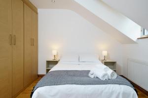 a bedroom with a bed with white sheets and two lamps at Flat in London in London