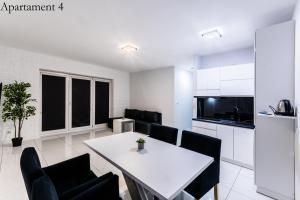 Il comprend une cuisine et une salle à manger avec une table et des chaises blanches. dans l'établissement Apartamenty Katowice by Lantier - Bytom - Chorzów, à Bytom