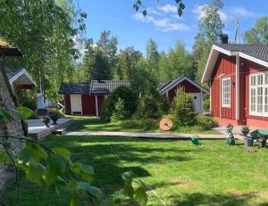 a backyard with a red house and a yard with a playground at Carpe Diem Guest Cottage in Östhammar