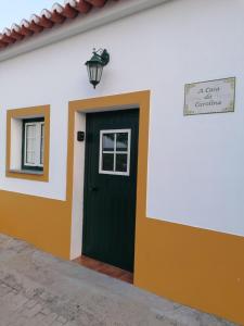 budynek z zielonymi drzwiami i znakiem ulicznym w obiekcie A casa da Carolina II w mieście Mértola