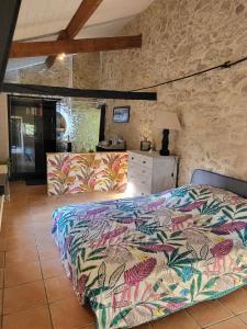 1 dormitorio con cama y pared de piedra en La hulotte de Labarthe, en Mazères