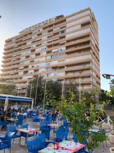 un grande edificio con tavoli e sedie di fronte di Playa de San Juan JULIA ad Alicante