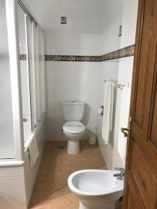 a white bathroom with a toilet and a sink at Hospedería Nuestra Sra de las Caldas in Las Caldas de Besaya