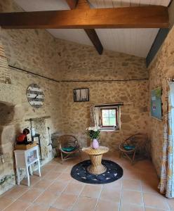 Habitación con paredes de piedra, mesa y sillas. en La hulotte de Labarthe, en Mazères