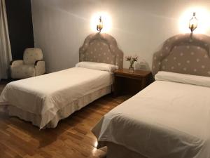 a bedroom with two beds and a chair and lights at Hospedería Nuestra Sra de las Caldas in Las Caldas de Besaya