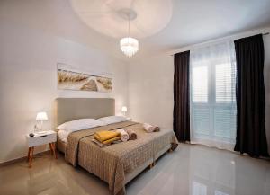 a bedroom with a bed and a chandelier at Sea Front Apartments Ivana in Rogoznica