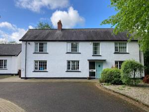 una casa blanca con una puerta verde en una calle en Large Country Farmhouse with Garden and Stream en Doagh