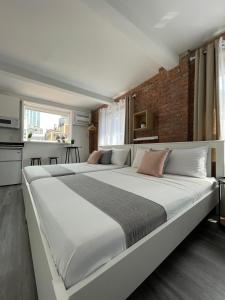 Cette chambre comprend un grand lit blanc et un mur en briques. dans l'établissement Hotel and the City, Rooftop City View, à New York