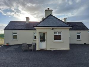 uma casa branca com duas cadeiras à frente em Patricia’s Country Cottage em Sligo