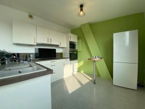 a kitchen with green walls and a white refrigerator at Superbe appartement avec vue panoramique sur Mers in Mers-les-Bains